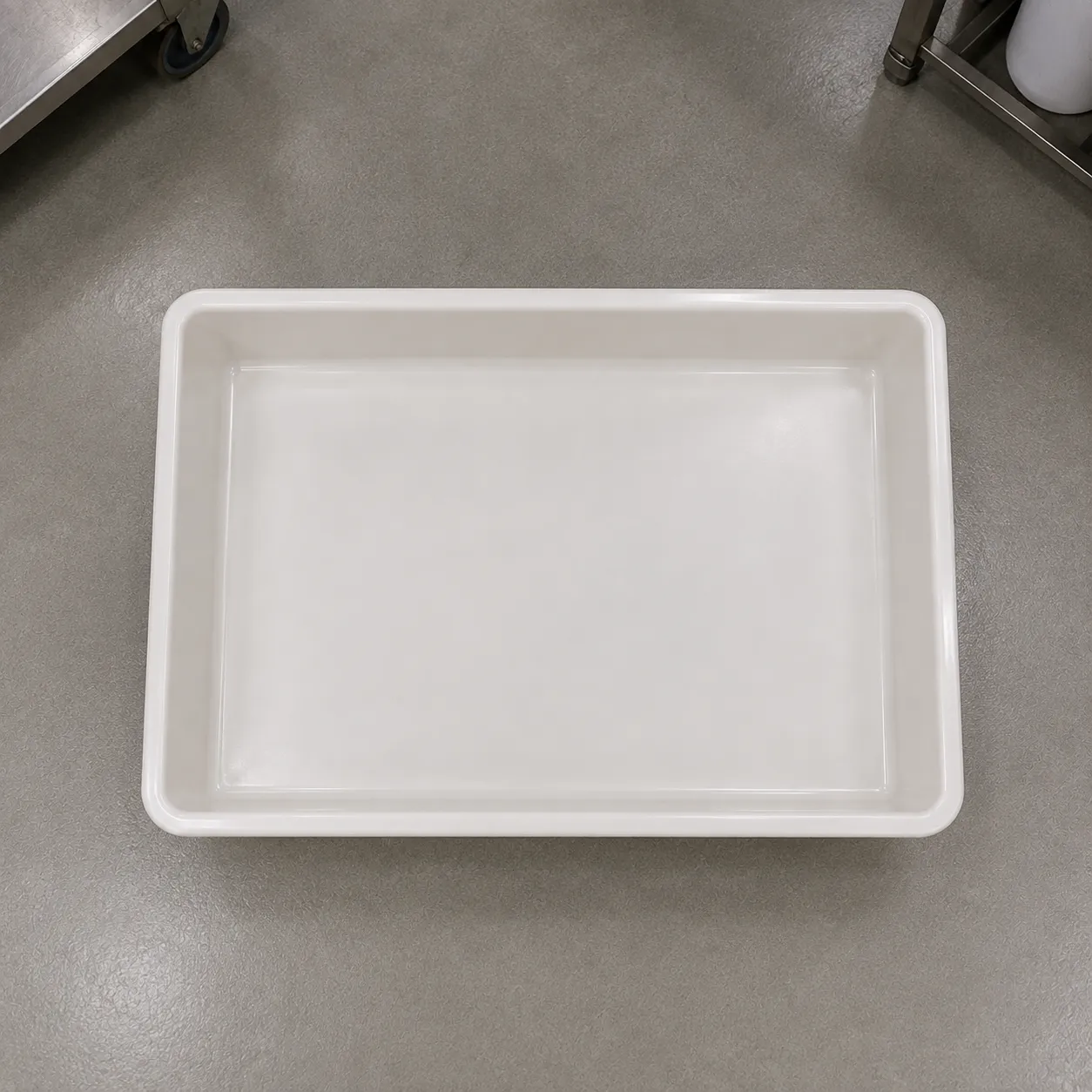 Vista superior de uma bandeja de contenção branca e retangular para produtos químicos.