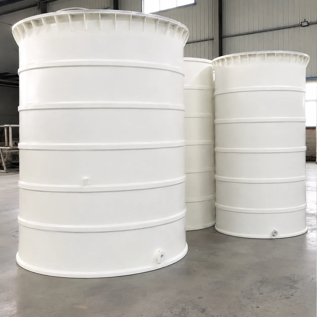Três tanques cilíndricos verticais para armazenamento de água potável, com tampas, reforços horizontais e conexões inferiores.